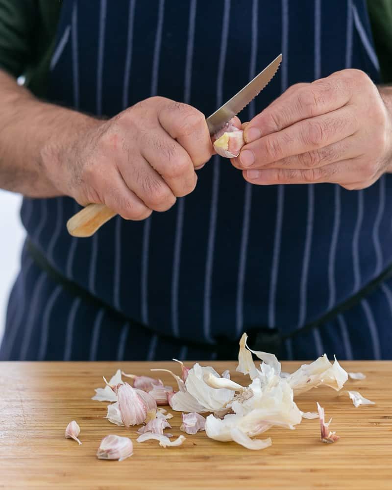 Person peeling garlic clove to make garlic herb butter