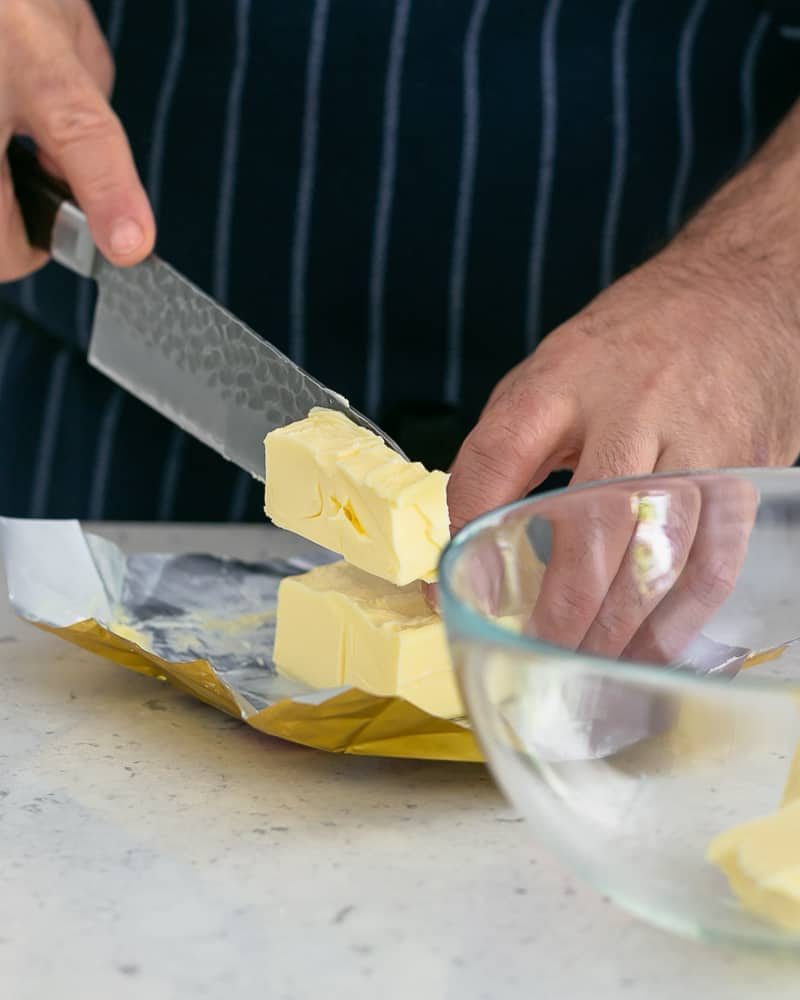 Person cutting butter with a knife to make Garlic Herb Butter
