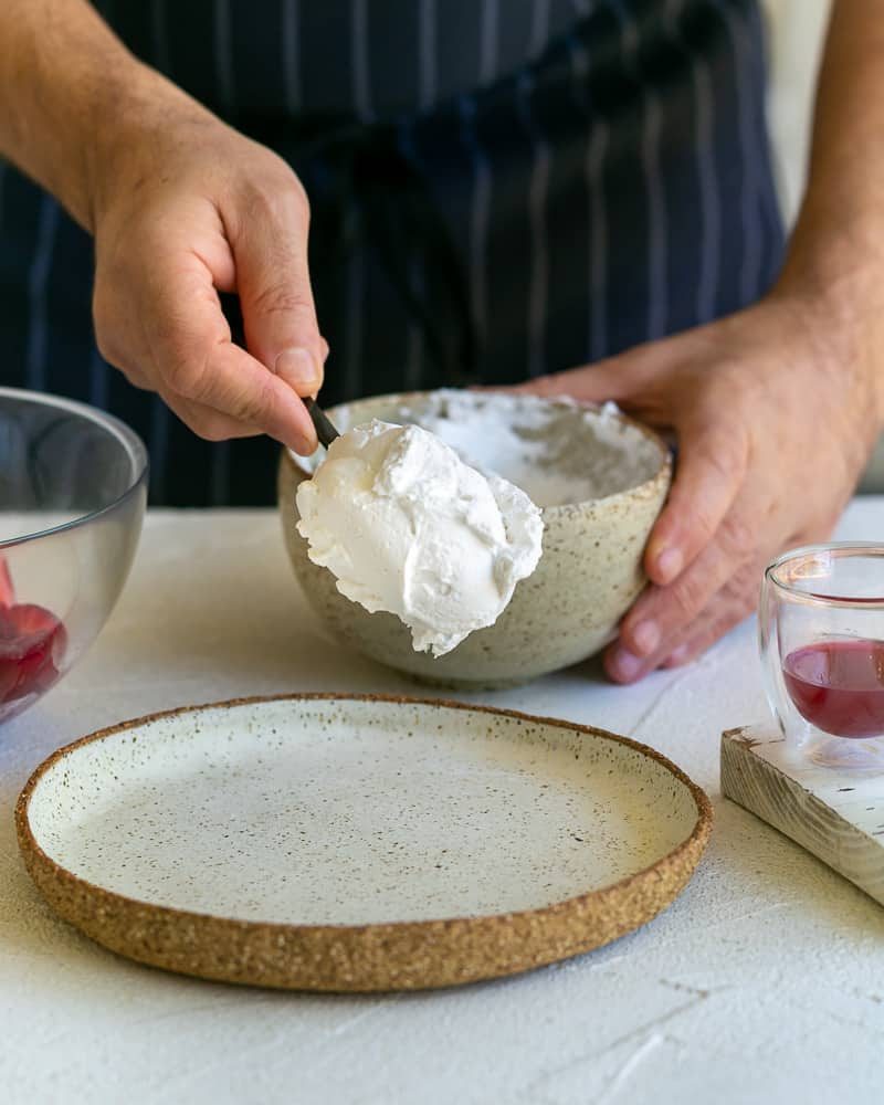 Adding a spoonful of whipped coconut cream on a plate