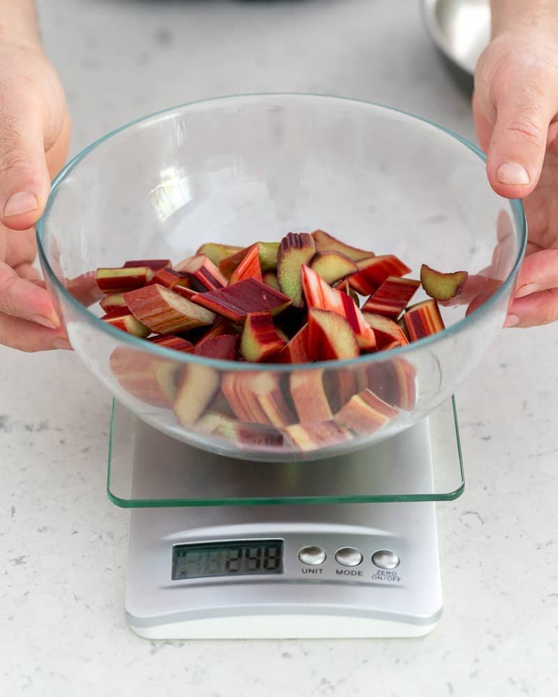 Weighing cut rhubarb in a bowl over a weighing scale