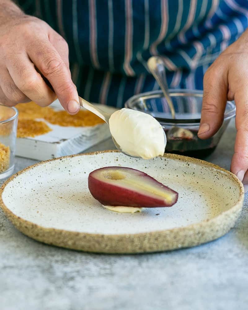 Spoonful of mascarpone on half a pear to assemble Spice poached pears with mascarpone