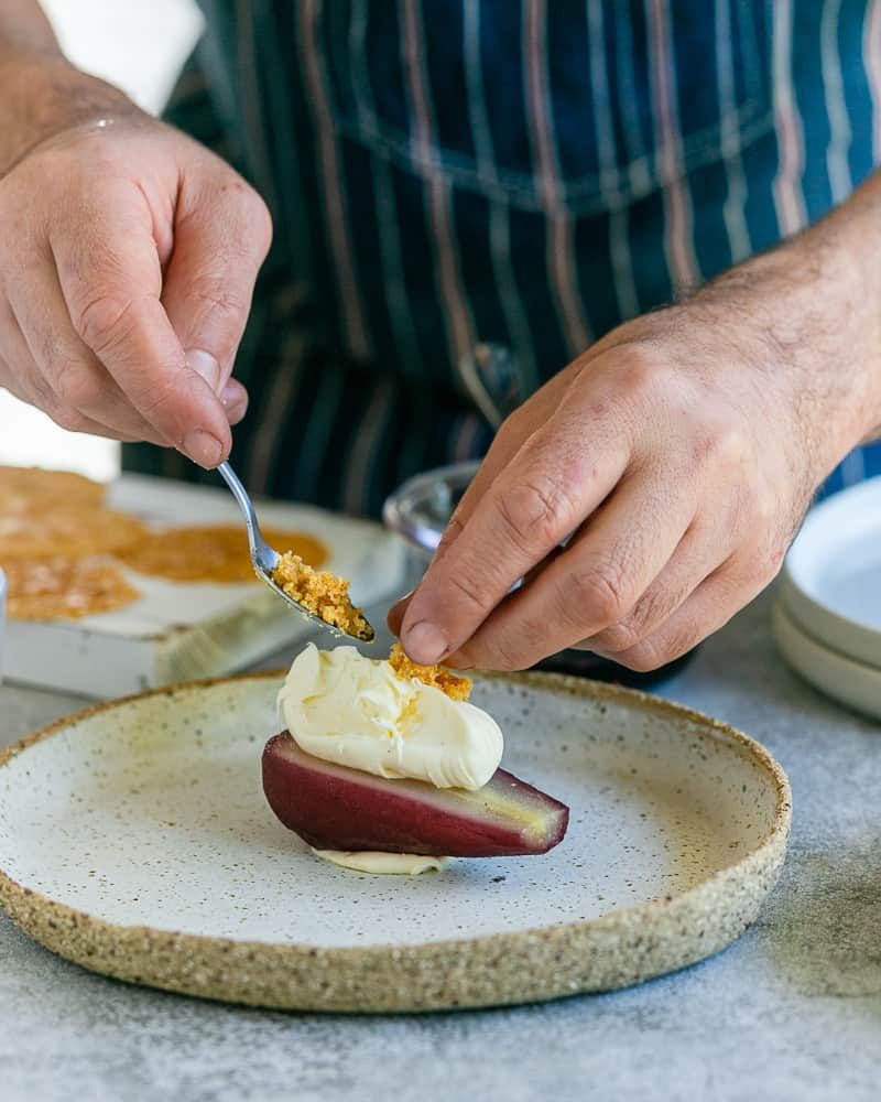 Sprinkling Macadamia nut brittle on the mascarpone on the half pear