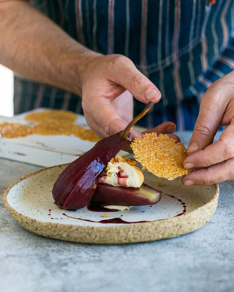 Placing the touile as garnish on teh spiced poached pears with mascarpone