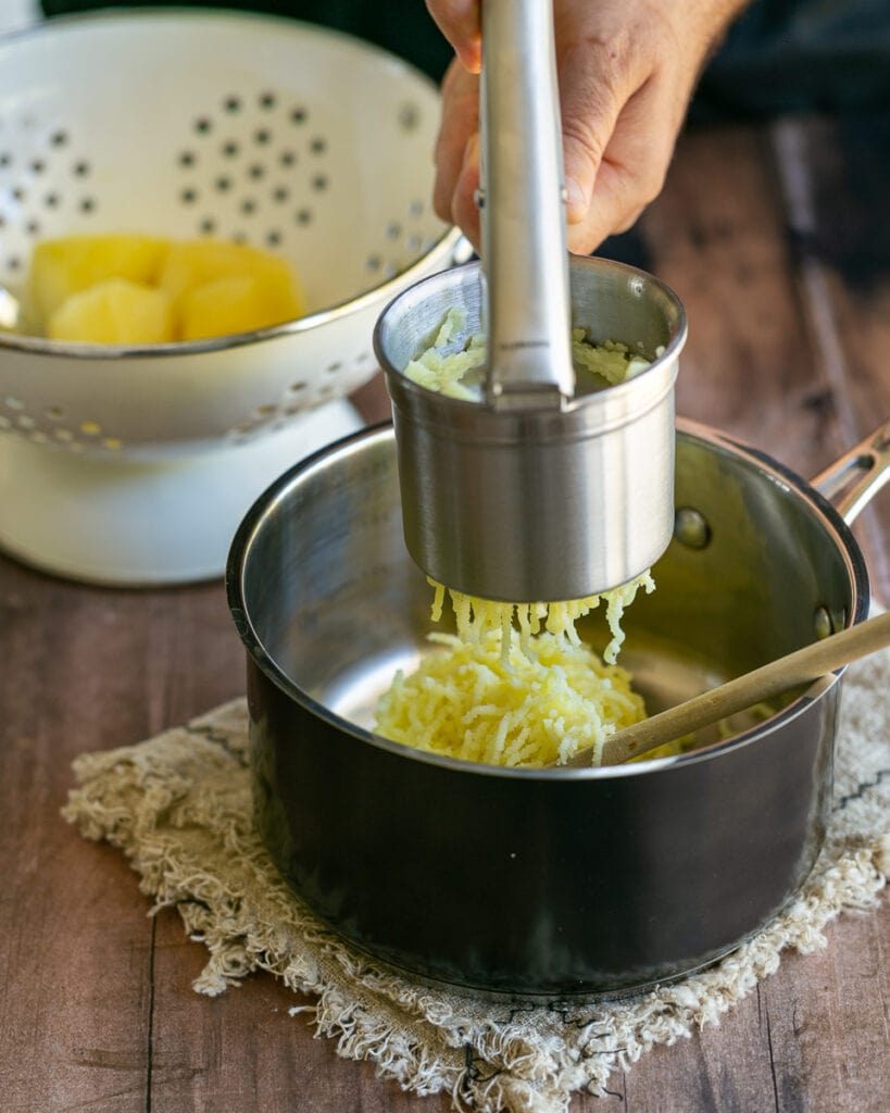 Passing boiled potato through potato masher