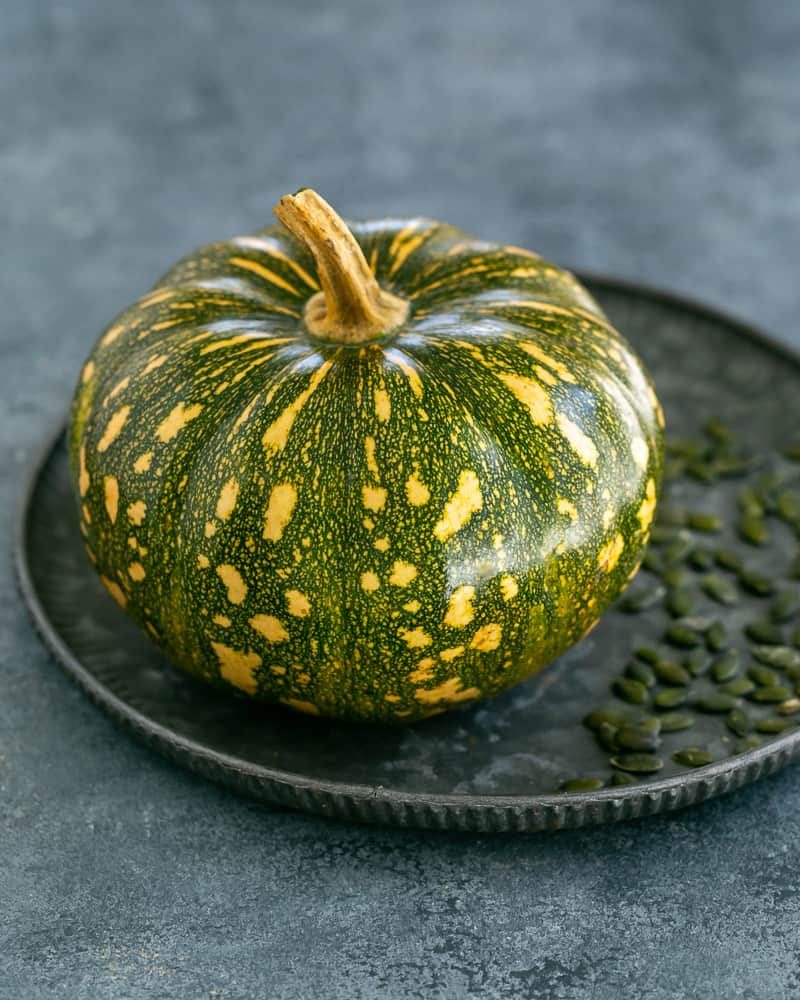 Whole jap pumpkin on a galvanized plate with pepita seeds