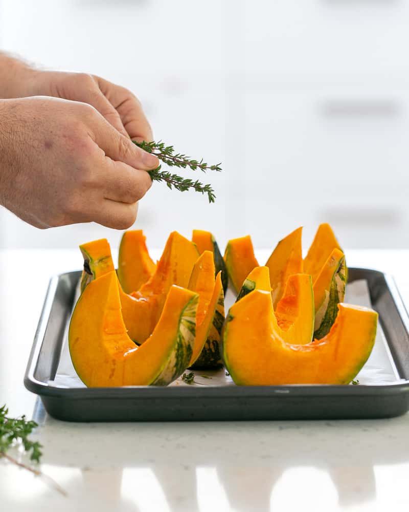 Fresh thyme sprinkled over Slicen pumpkins with salt and olive oil