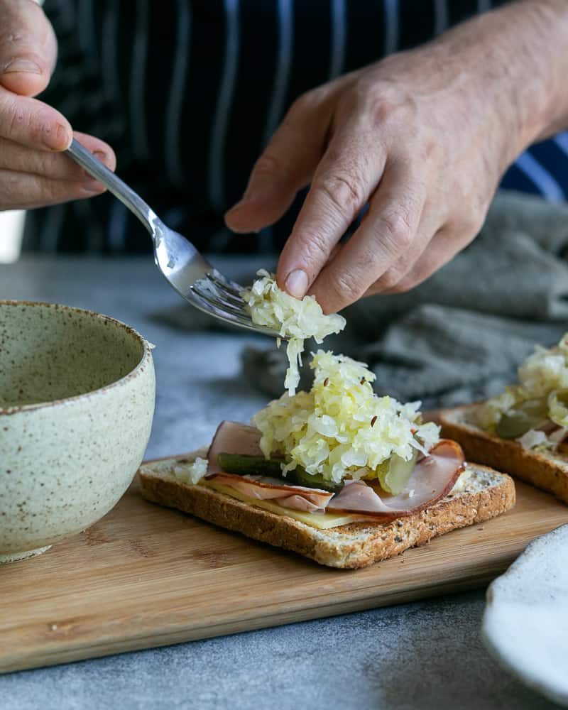 Using Sauerkraut as a sandwich filling with ham, cheese and pickles on a slice of toast