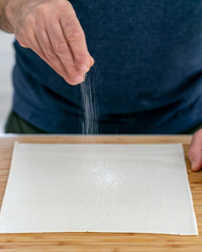 Person sprinkling sugar on rolled out puff pastry for Dulce de Leche Verrine with Banana and whipped Cream