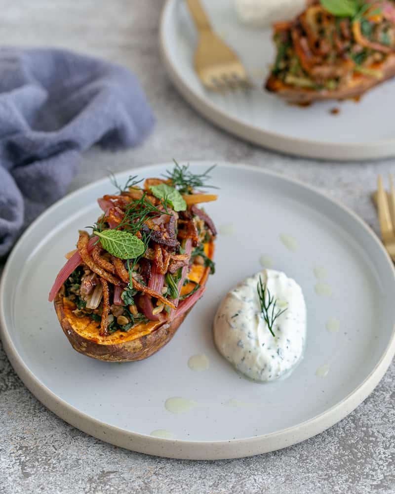 Baked Sweet Potato with Lentils and Swiss Chard served in a plate with labneh on the side