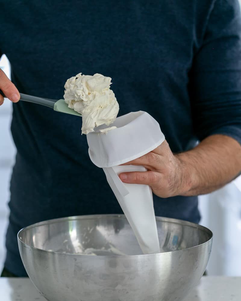 Vanilla whipped cream in piping bag to assemble Dulce de Leche Verrine with Banana and whipped Cream