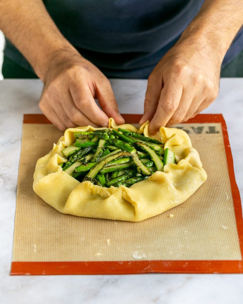 Folding the pastry to encompassing the asparagus and caramelised onions