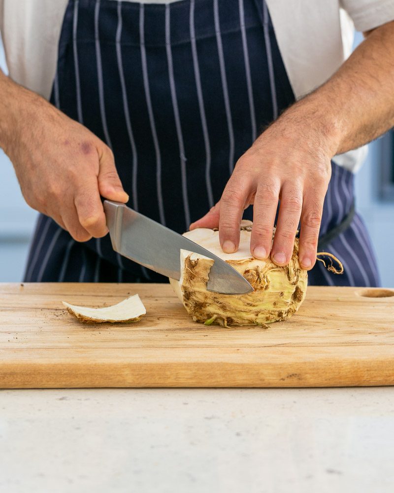 Peeling celeriac to prepare garnish for trout fillet