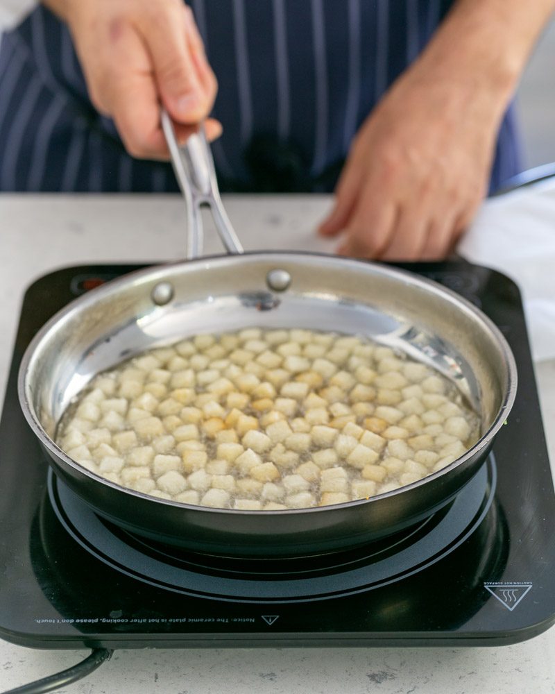 Dicing white bread to make croutons for the baked trout fillet