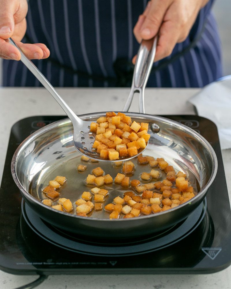 Frying bread croutons to garnish the baked trout fillet