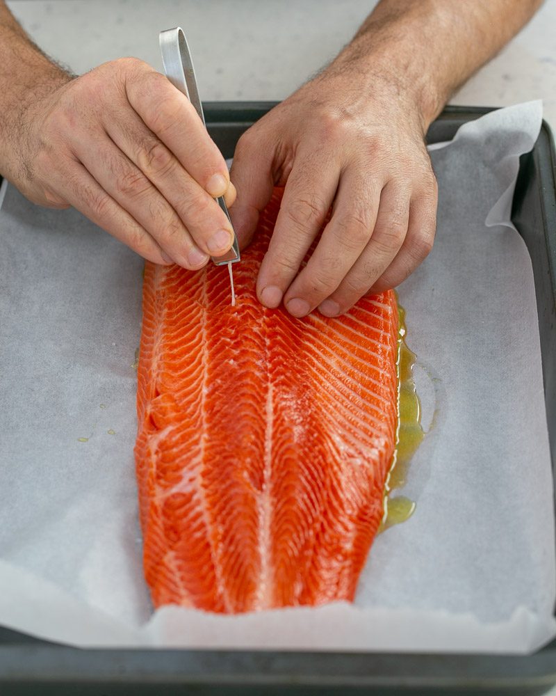 Taking out  bones using a tweezer from the trout fillet