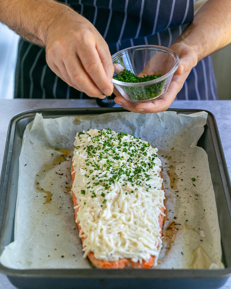 Sprinkling chopped chives on celeriac creme fraiche mix spread on trout filler