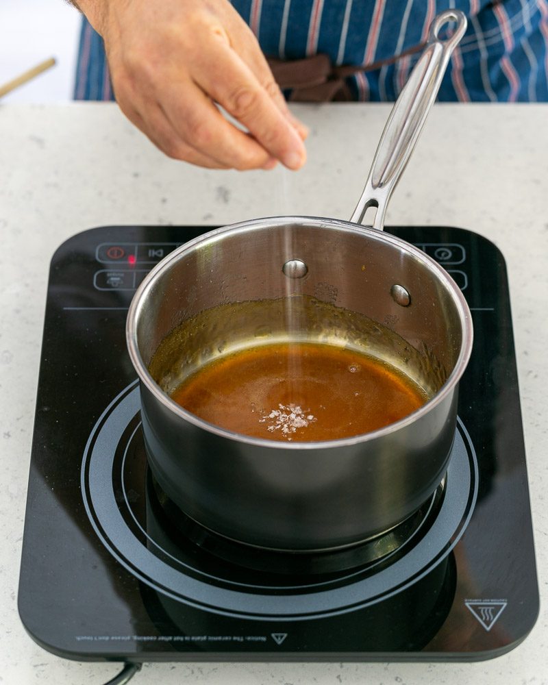Adding sea salt to caramel in the pan