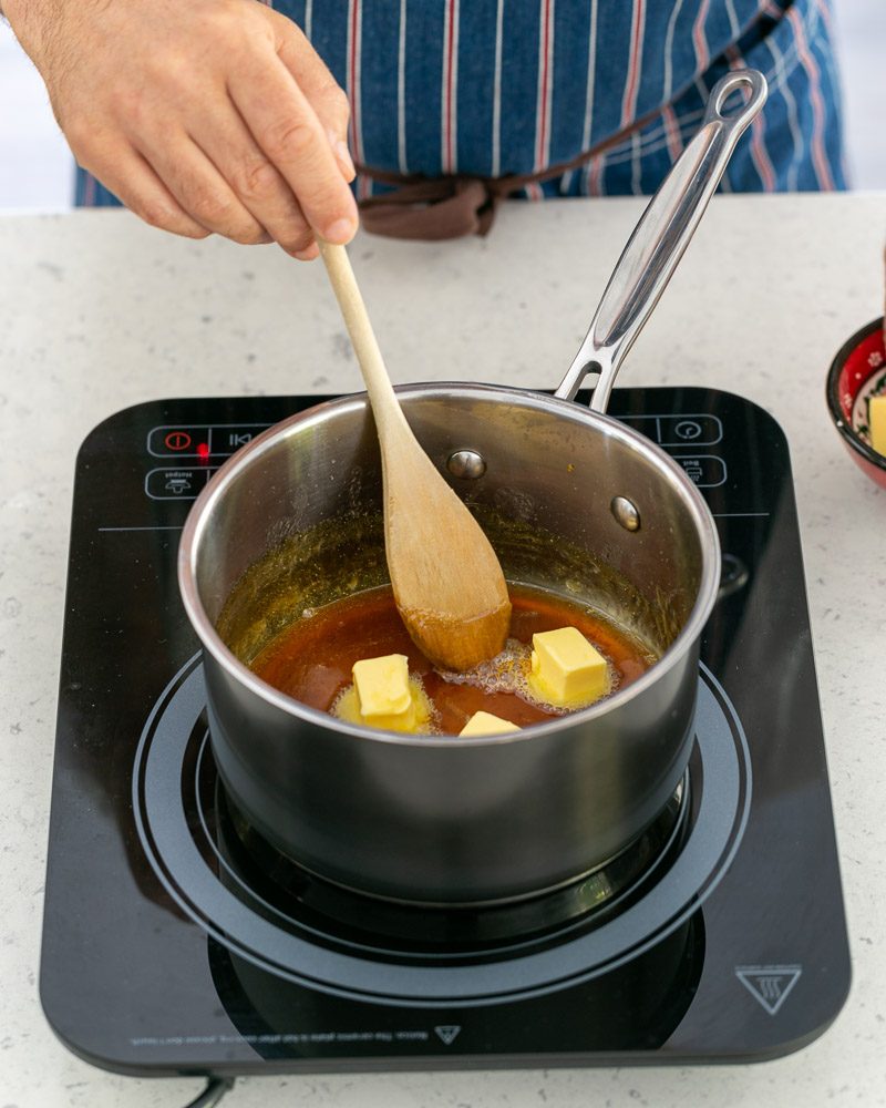 Adding butter cubes to caramel in the pan