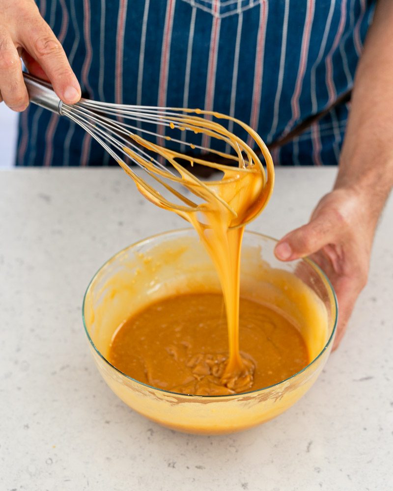 Mixing all ingredients with a whisk in a bowl for the recipe for salted caramel fondant