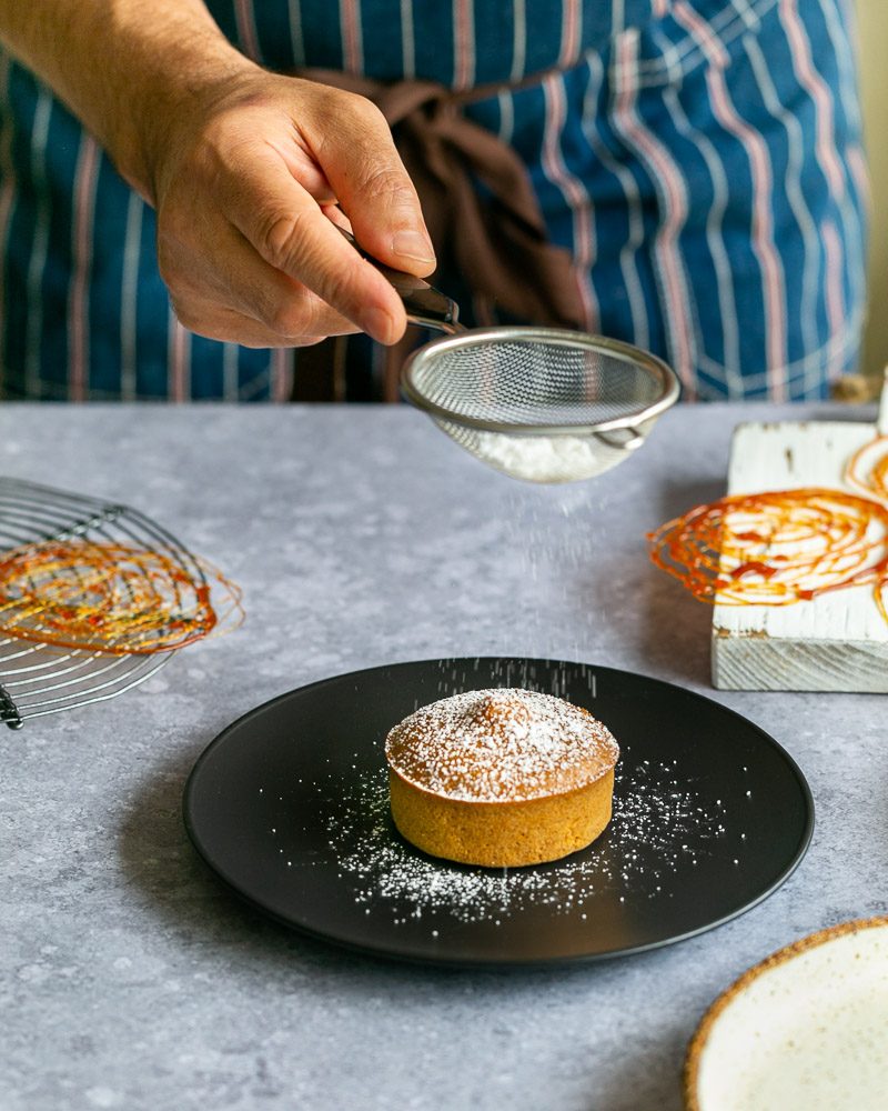 Sprinkling icing sugar on caramel fondant