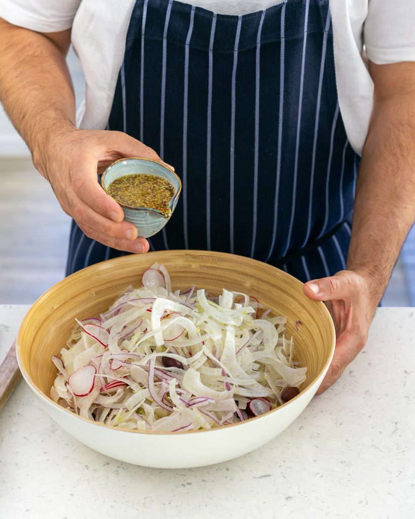 Salad dressing added to the salad in the bowl