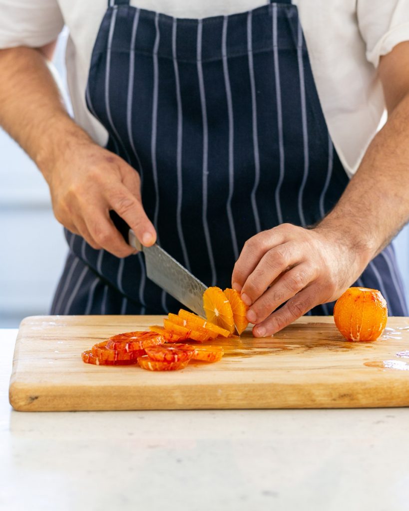 Cutting blood orange rounds with a knife