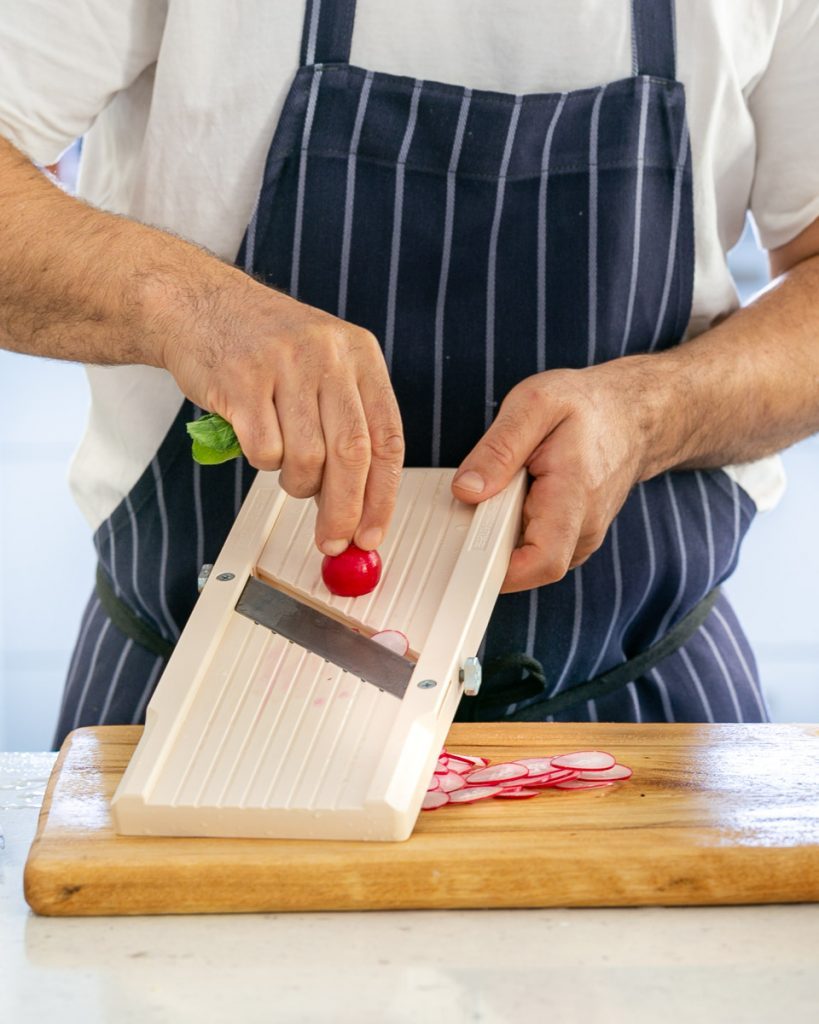 Slicing red radish on a Japanese mandoline