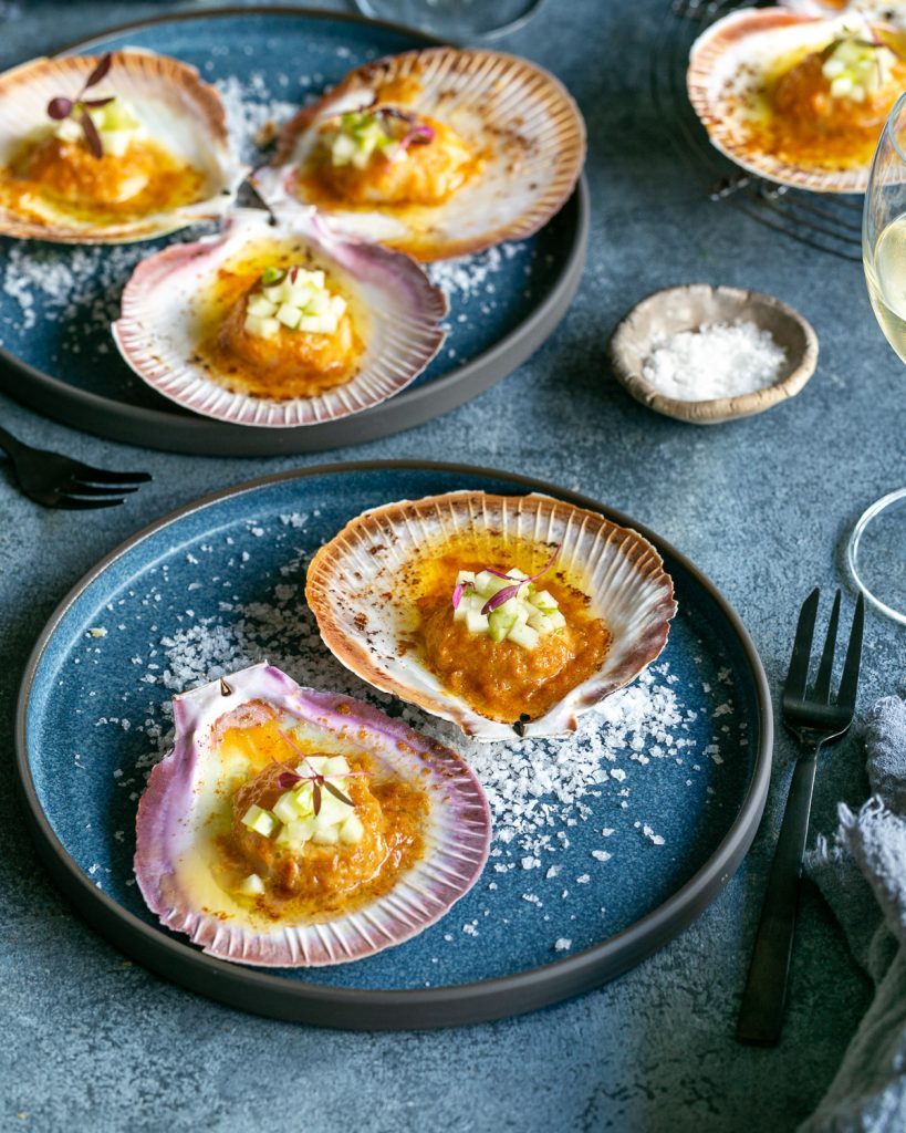 Oven Baked Scallops with Miso and Ginger Butter served in plates with a glass of wine