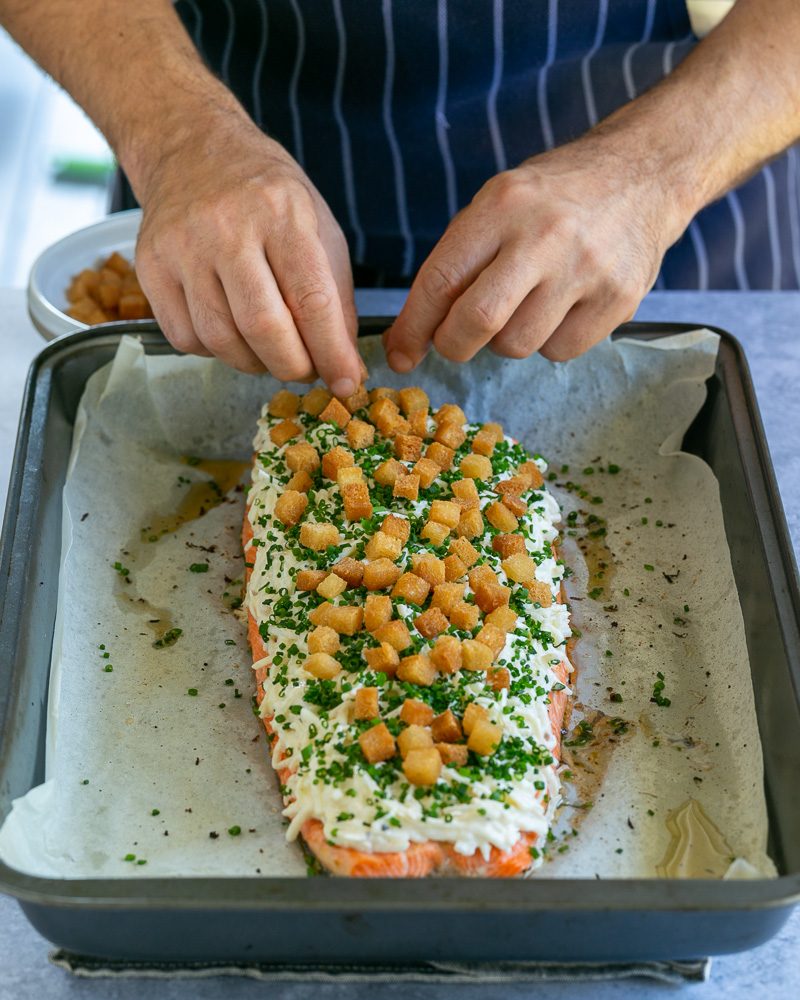 Garnishing the baked trout fillet with chopped chives and croutons