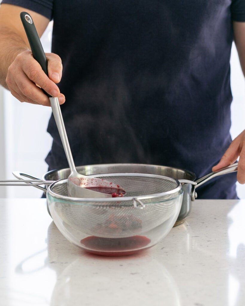 Straining berry soup through sieve
