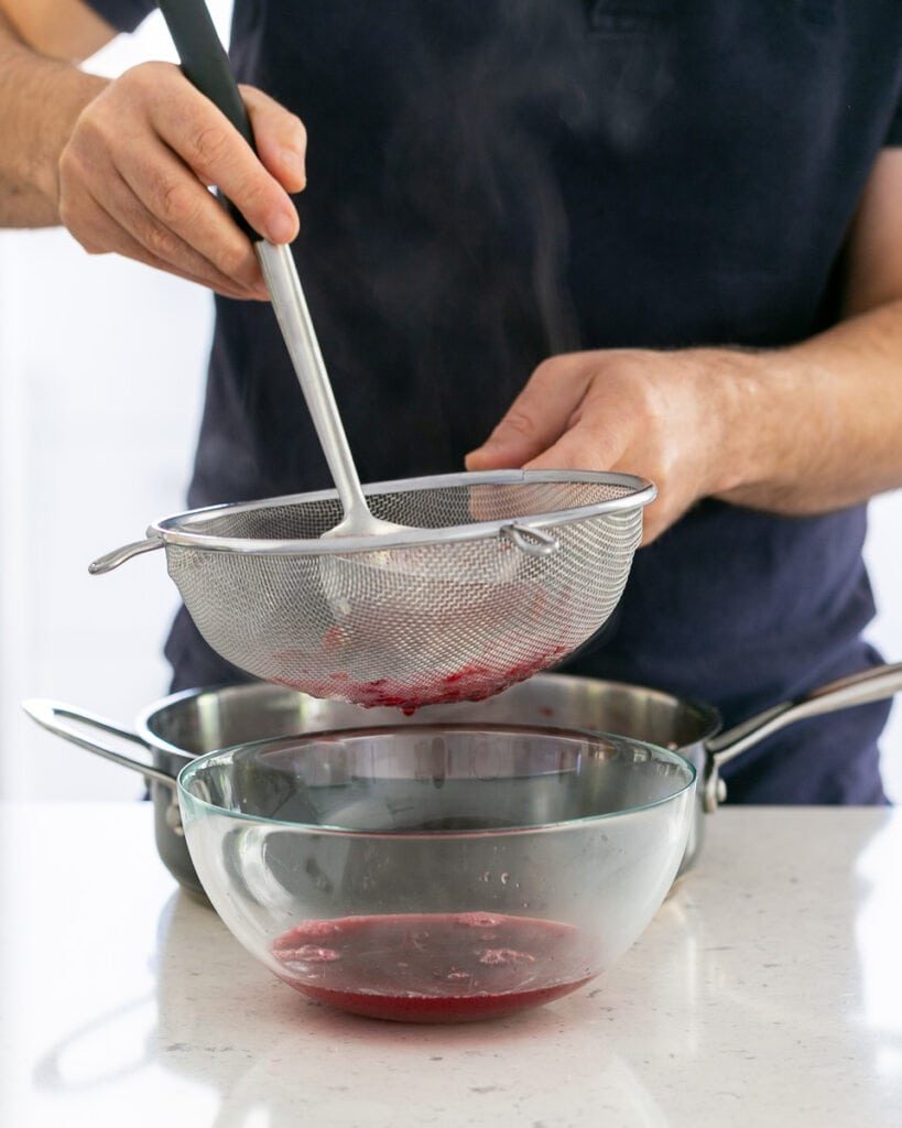 Straining berry soup through sieve