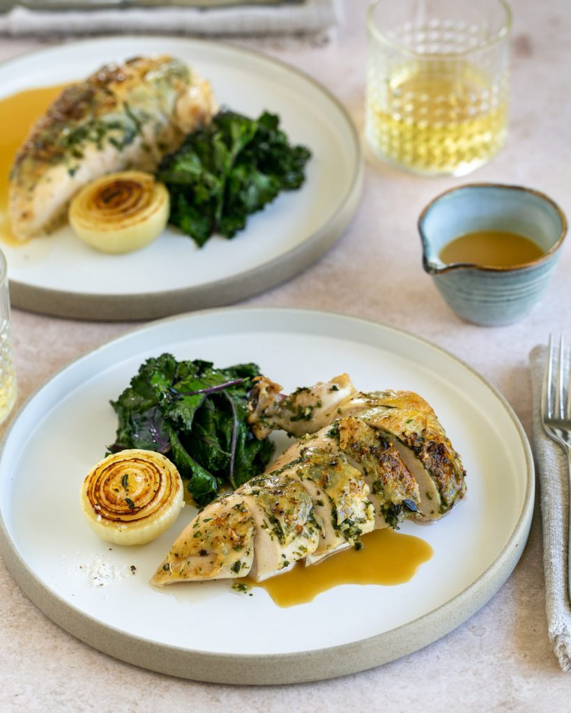 Chicken gravy served with roasted chicken breasts and kale 