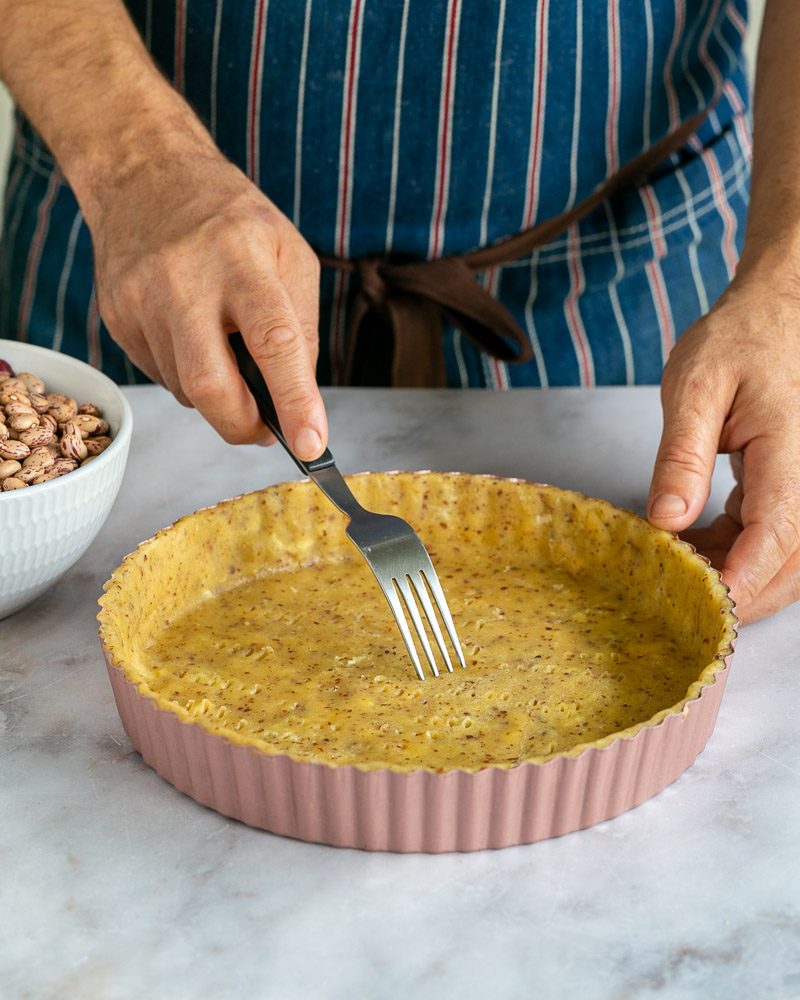 Pricking the tart with a fork to blind bake