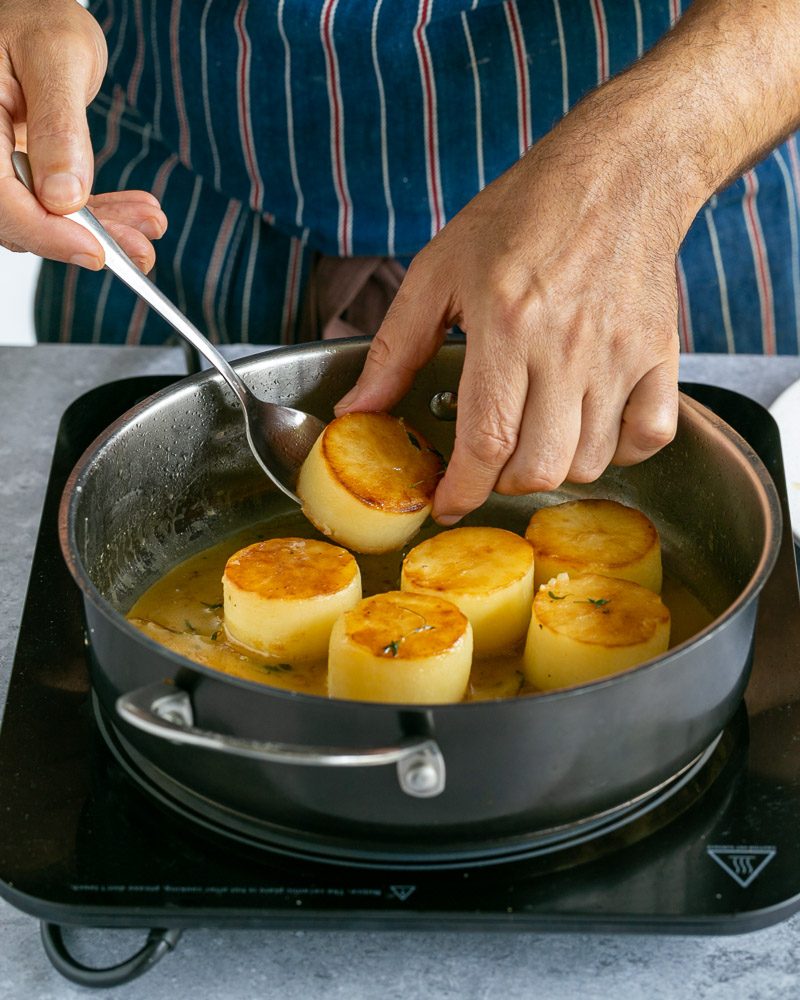 Adding the potatoes back to the reduced glaze in pan