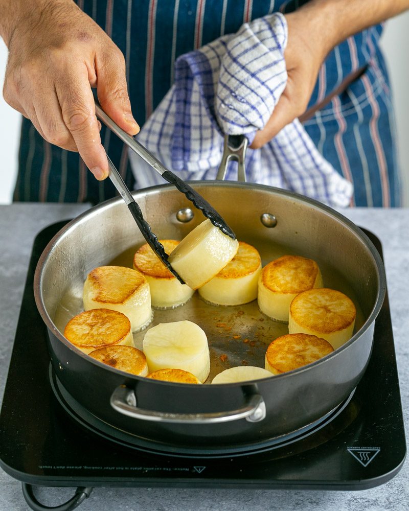 Searing potatoes in a pan until crispy brown