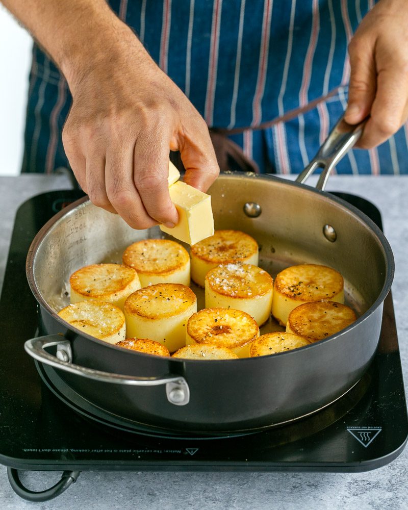 Adding butter to the pan with potatoes