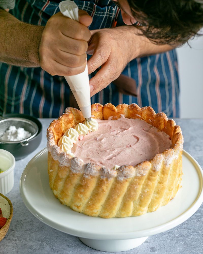 Decorating the cake with whipped cream using piping bag