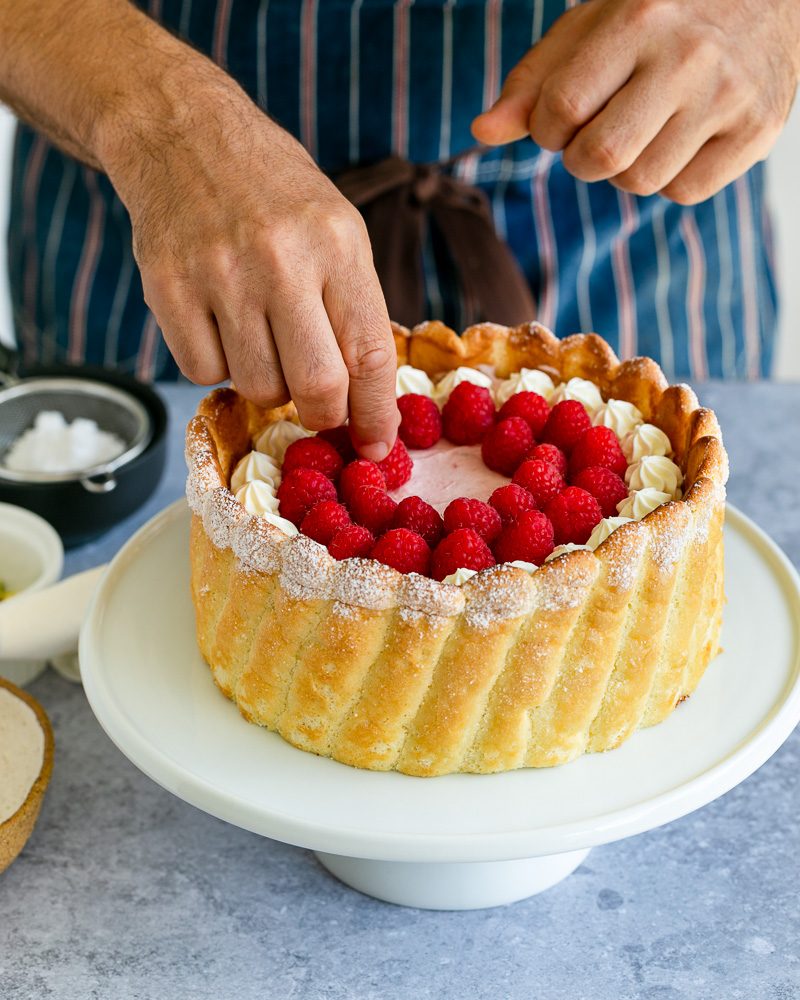 Decorating cake with fresh raspberries