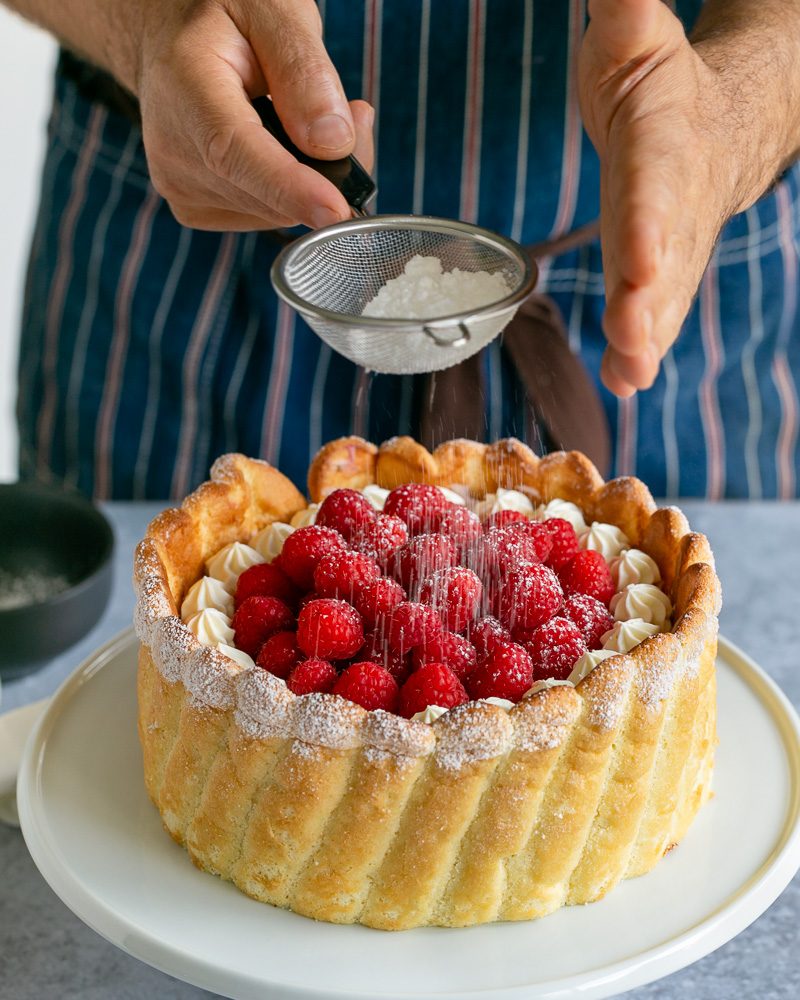 Dusting decorates cake with icing sugar