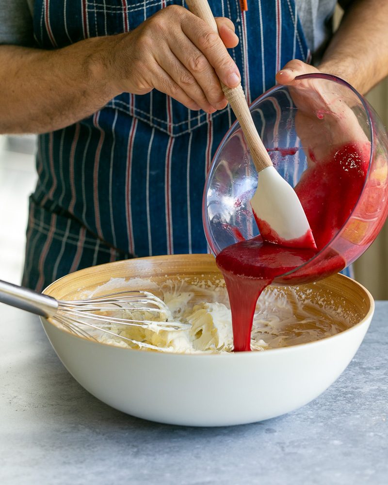 Mixing the raspberry coulis with whipped cream for the charlotte filling