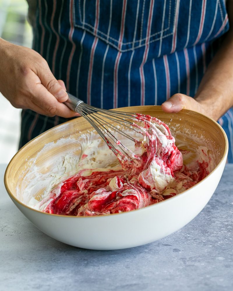 Mixing the raspberry coulis with whipped cream for the charlotte filling