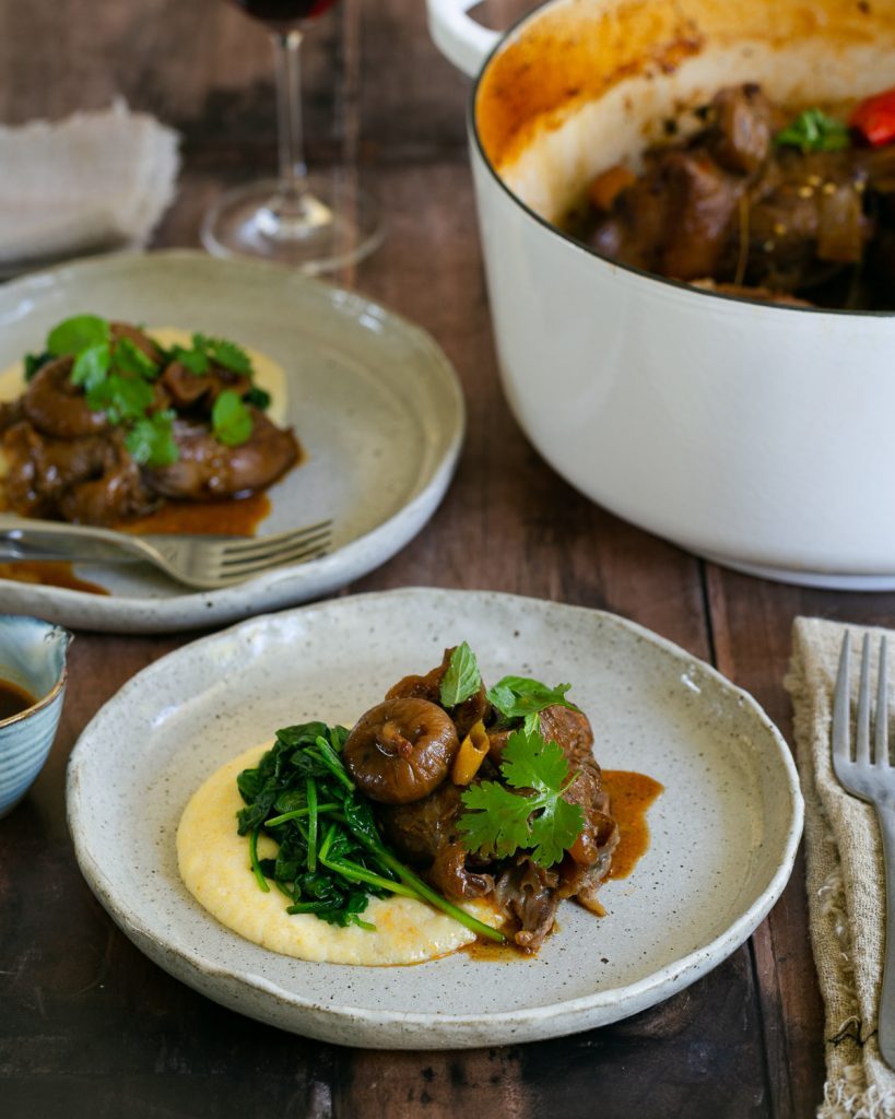 Lamb shanks served with polenta and spinach in a plate
