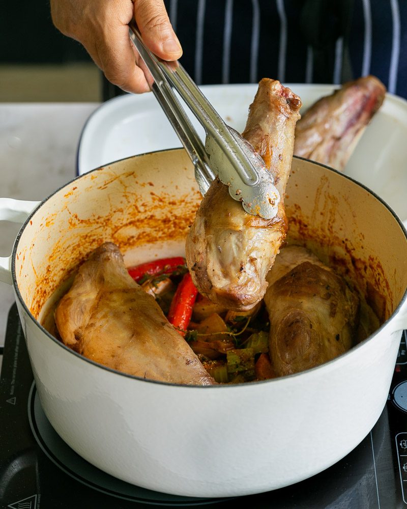 putting seared lamb shanks into the pot