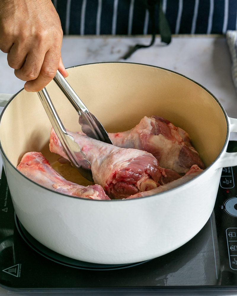 Searing lamb shanks in a white pot