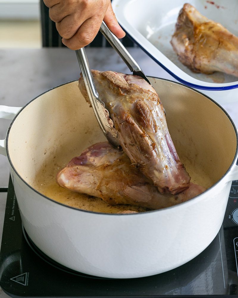 Removing the seared shanks from the pot
