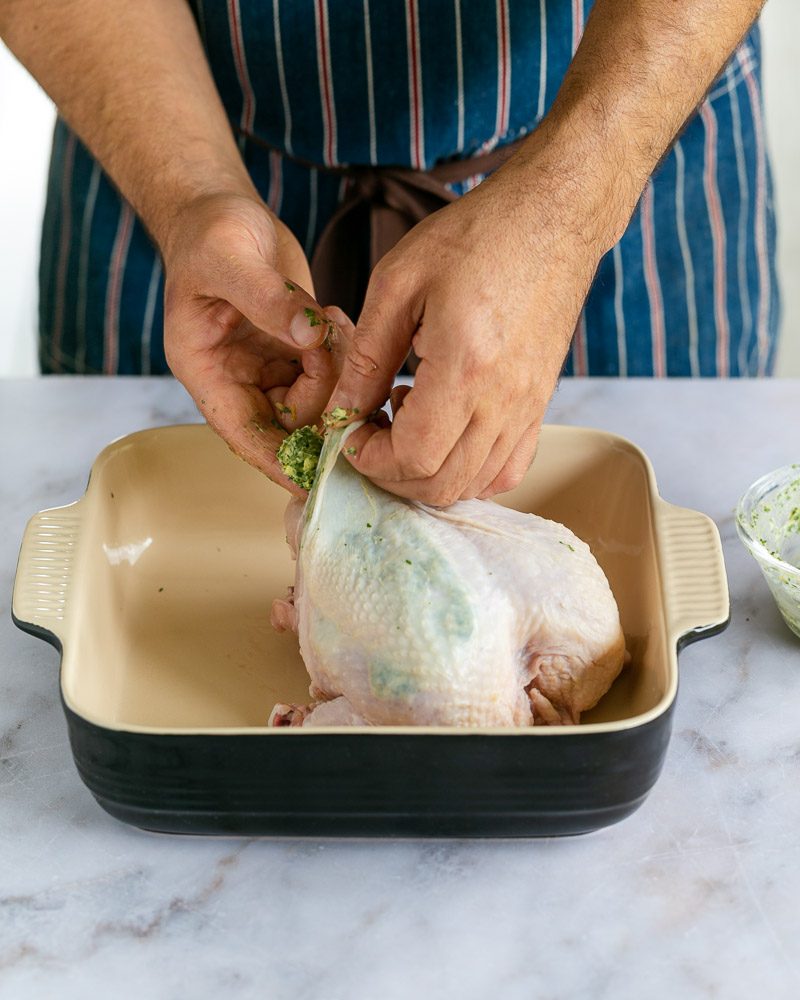 Inserting the garlic herb butter under chicken skin