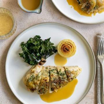 Chicken breast served with gravy and kale on a plate