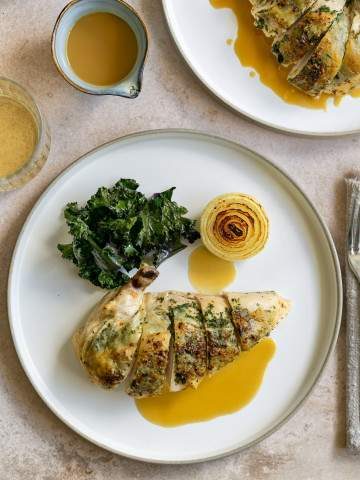 Chicken breast served with gravy and kale on a plate