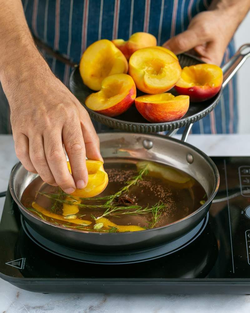 cut peach halves in poaching liquid