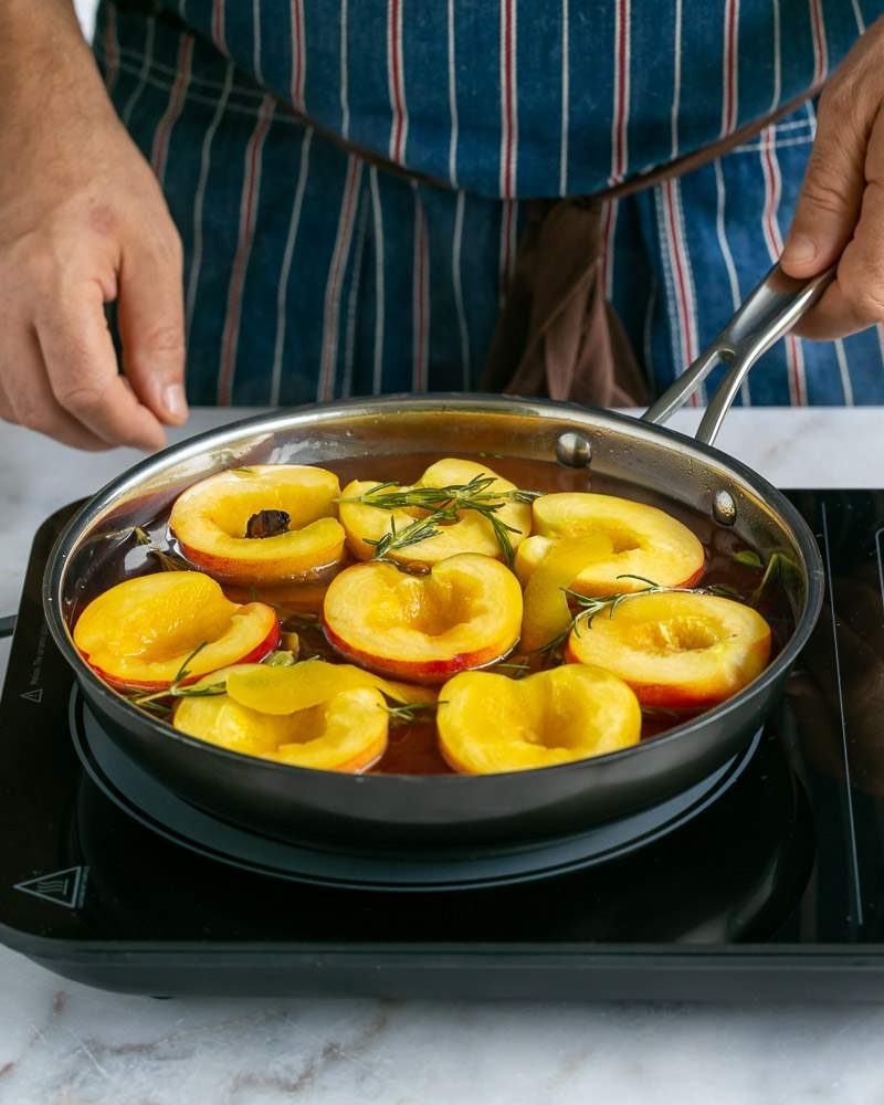 cut peach halves in poaching liquid